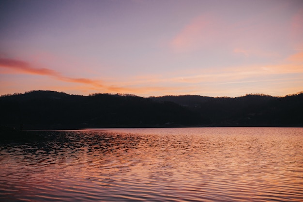 Free Photo sea surrounded by hills under the sunlight during a beautiful sunset