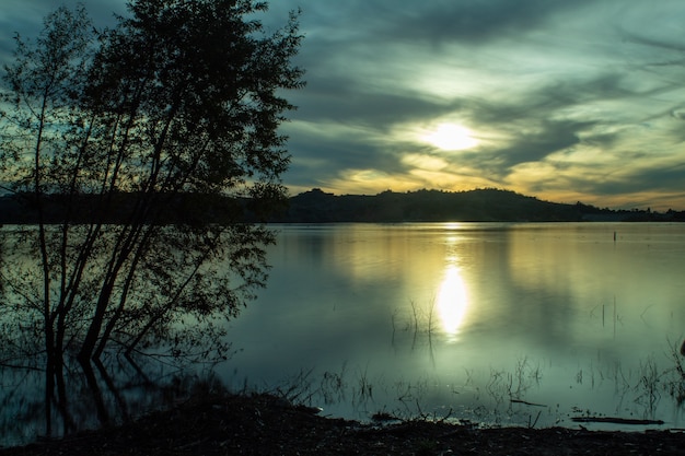 Free Photo sea surrounded by hills under the sunlight and a cloudy sky in the evening