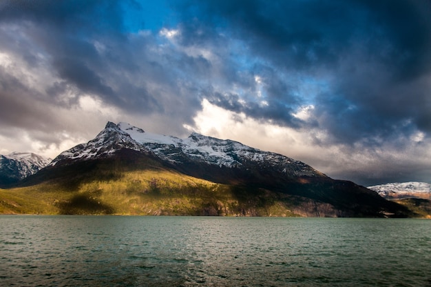 Free Photo sea surrounded by mountains under a cloudy sky in patagonia, chile