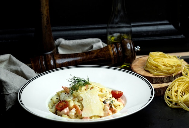 Free Photo seafood fettuccini with creamy sauce, parmesan topped with cherry tomato and dill