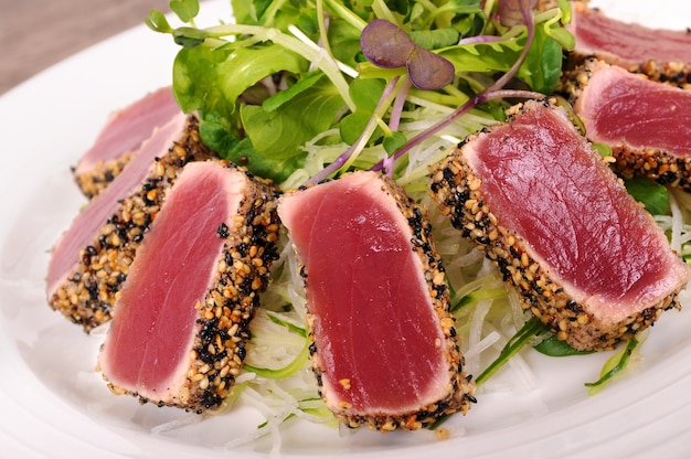 Free Photo seared tuna coated with sesame seeds with green salad