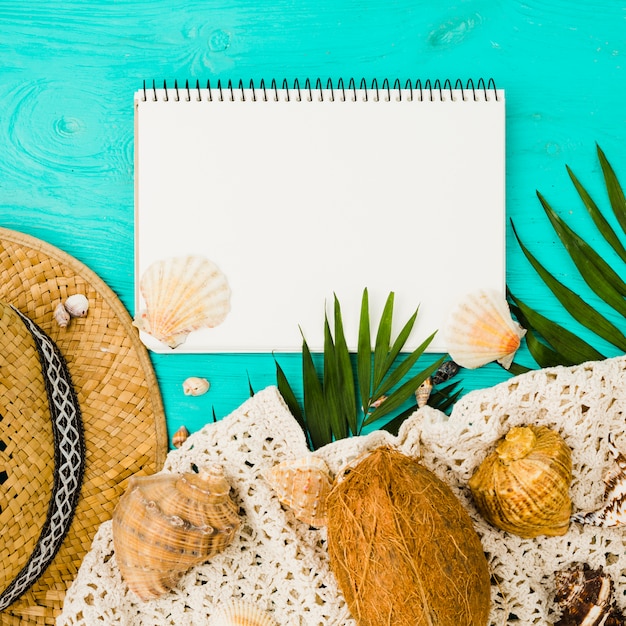 Free Photo seashells and hat with plants near fruit and textile with notepad