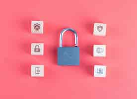 Free photo security concept with lock, icons on wooden cubes on pink table flat lay.