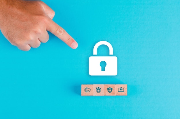 Free Photo security concept with wooden blocks, paper lock icon on blue table flat lay. man hand pointing.