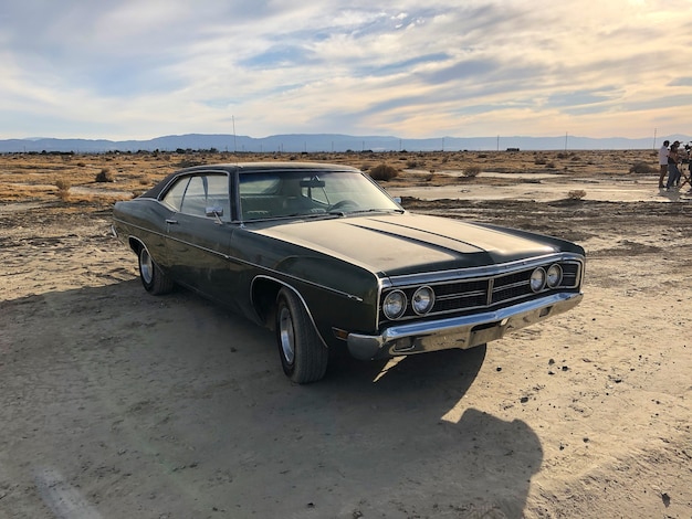 Sedan parked at a deserted area under a cloudy sky