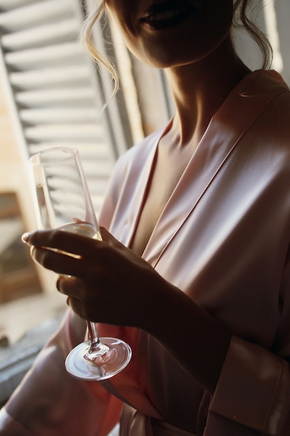 Free photo seductive lady in pink silk robe holds champagne flute