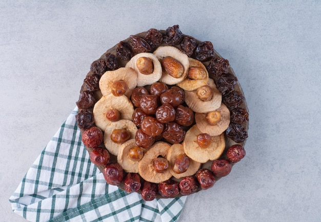 Selection of dry fruits on a platter on concrete surface.