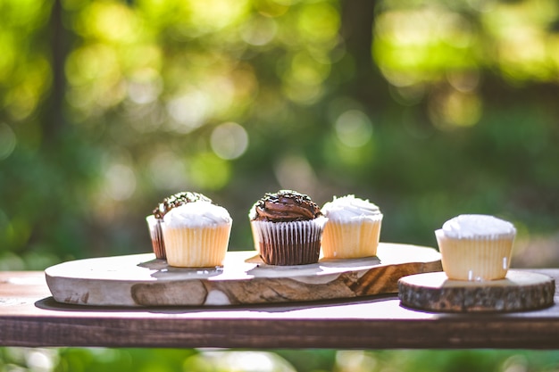 Free photo selective closeup shot of chocolate and cream cupcakes on a wooden surface