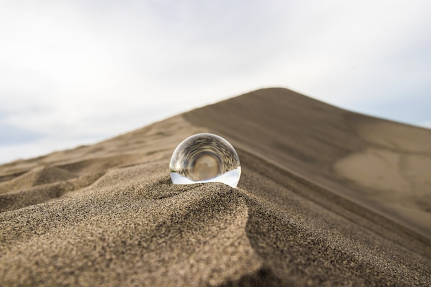 Free Photo selective closeup shot of a crystal ball on a sandy surface