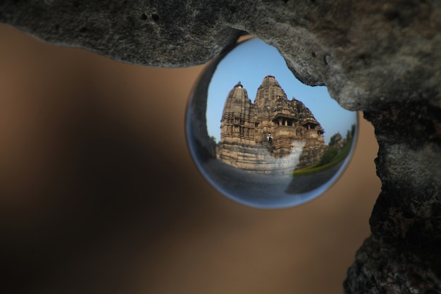 Free Photo selective closeup shot of the reflection of temple in orcha, india in glass ball hanging from a rock