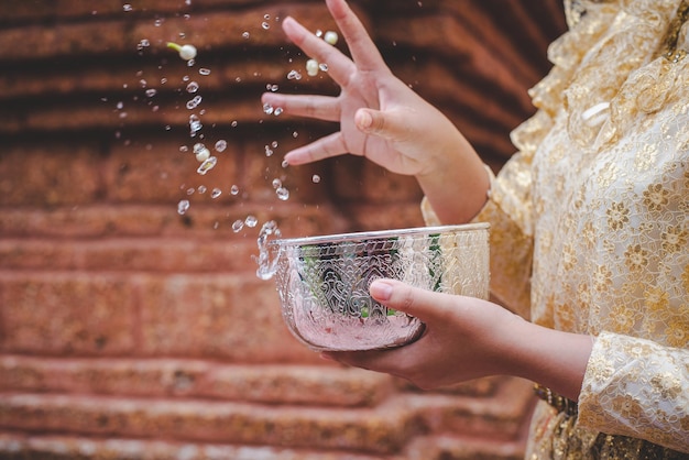 Selective focus and close up Female hand holding water bowl and splashing water in temples and preserve the good culture of Thai people during Songkran festival Thai New Year Family Day in April