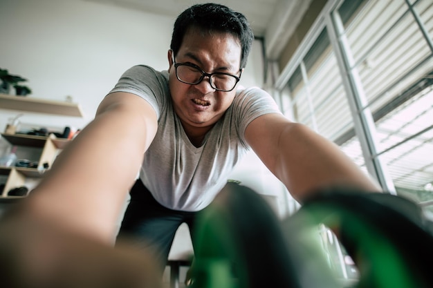 Selective focus Funny overweight man wearing eyeglasses is workout with ABS handroller for healthy copy space