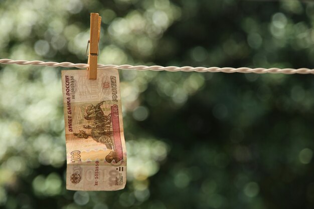 Selective focus shot of a banknote hung from a wire with a clothespin