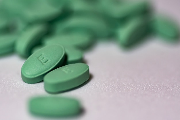 Free Photo selective focus shot of green pills on a white surface