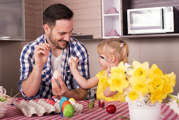 Free Photo selective focus shot of a happy dad and daughter painting easter eggs