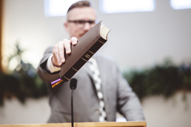 Selective focus shot of a male standing and holding a book in hands