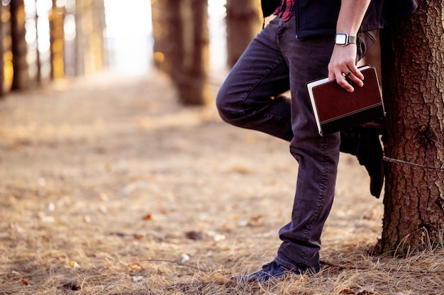 Selective focus shot of a man holding a book posing in a forest