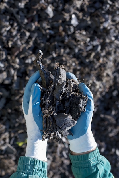 Free photo selective focus shot of a person wearing gloves holding shredded rubber tires