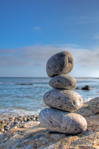 Selective focus shot of piled stones in a seashore with a blurred blue sky