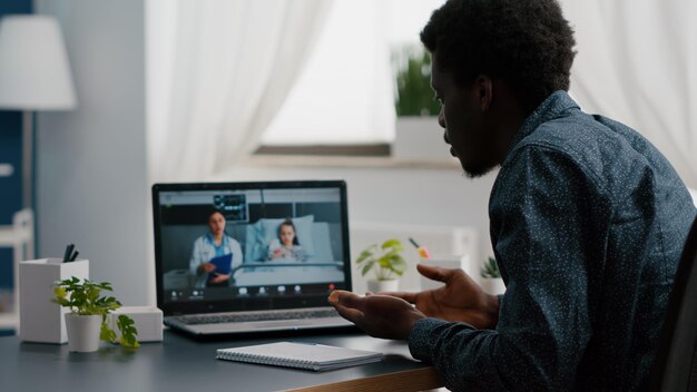 Selective focus on worried african american dad for little girl in hospital ward, talking with doctor on video conference call with webcam app remote screen for family connection. Family doctor consul