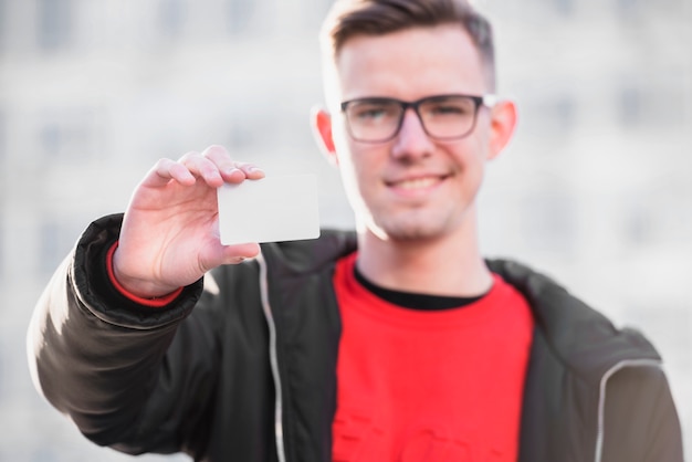 Selective focus of a young man showing white blank visiting card