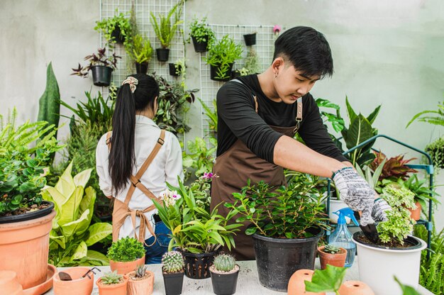 Selective focus, Young man use shovel transplant and take care house plant, woman working behind him