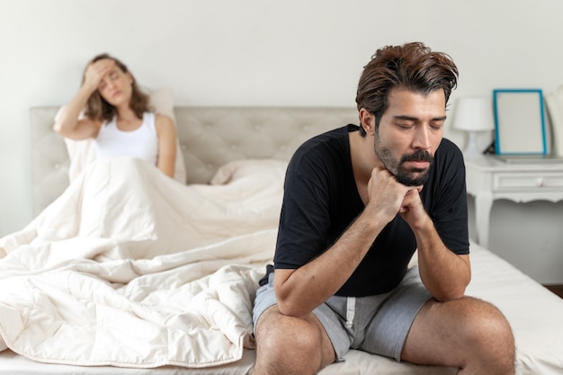 Selective husband sitting on bed with feel bored about her wife  