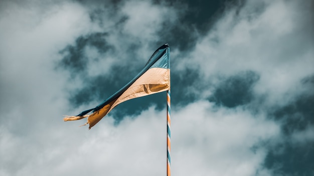 Selective shot of the yellow and blue flag of Ukraine on flagpole on the background of a cloudy sky