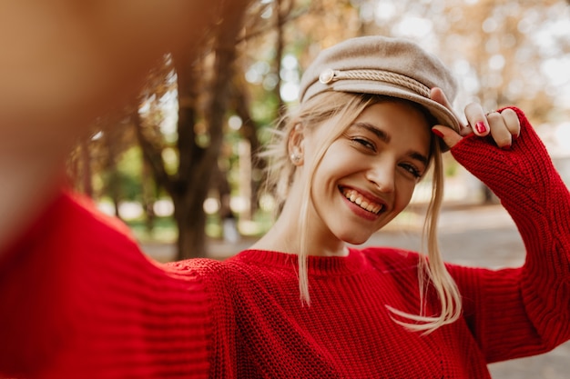 Free photo selfie of a beautiful blonde smiling in the park. stunning woman in seasonal clothes having fun in autumn.