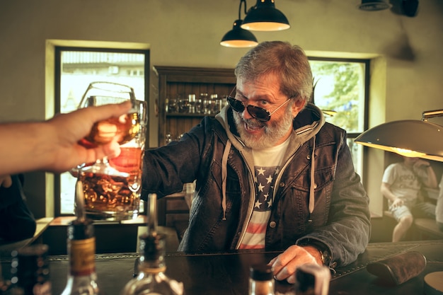 Free photo the senior bearded male drinking beer in pub