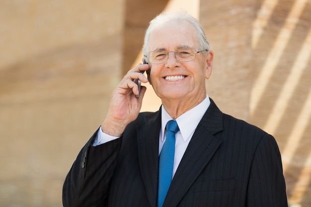 Free photo senior business man talking on the phone and smiling