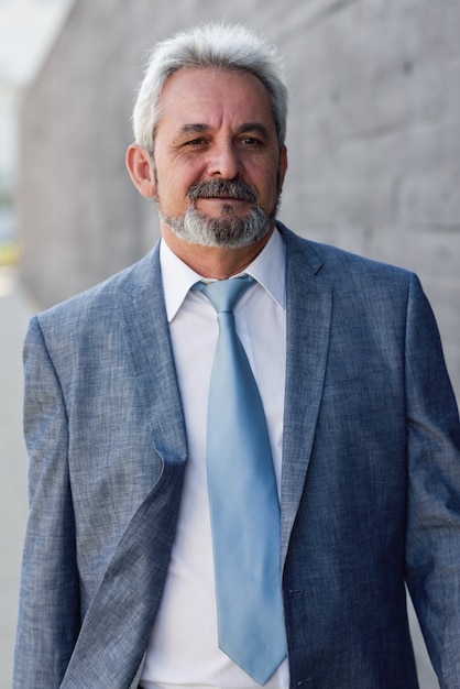 Free Photo senior businessman walking outside of modern office building.