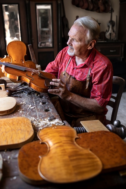 Senior carpenter checking violin instrument he is about to repair