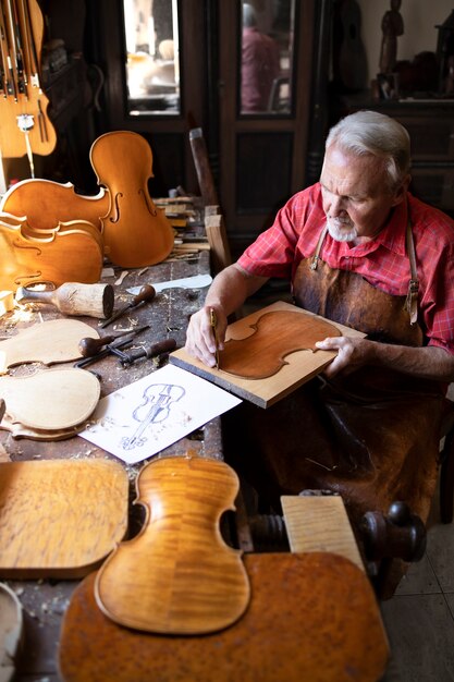 Senior carpenter craftsman making violin music instrument in his old-fashion carpenter's workshop