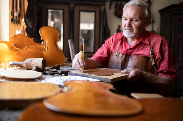 Senior carpenter craftsman making violin music instrument in his old-fashion carpenter's workshop