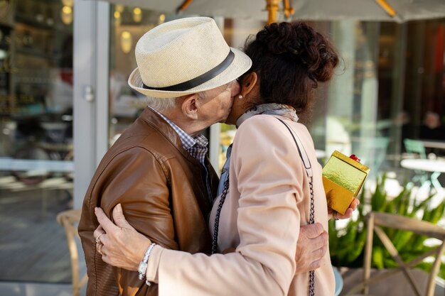 Free photo senior couple hugging and kissing while being on a date