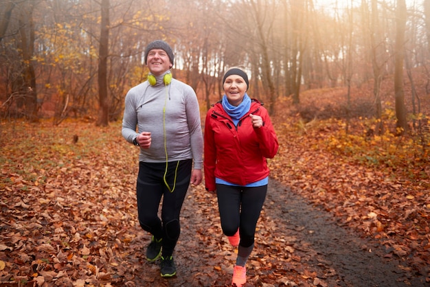 Senior couple jogging among forest path