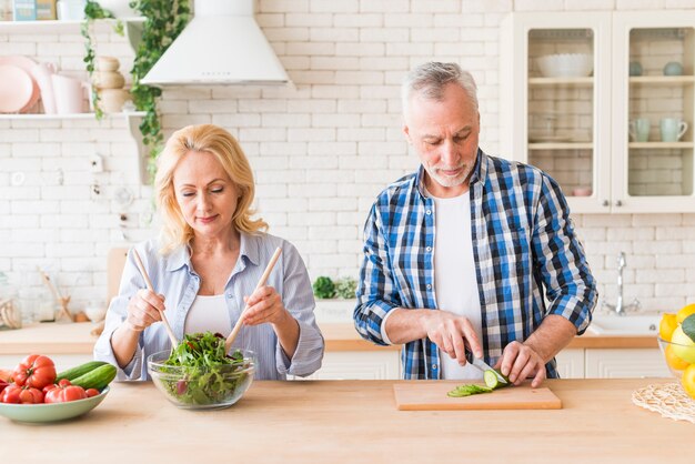 Senior couple preparing the salad in the modern kitchen