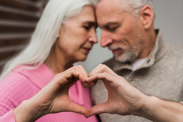 Senior couple showing heart shape of hands