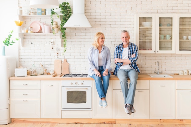 Senior couple sitting on kitchen counter