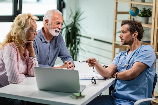 Senior couple talking with their doctor while he is showing them something on a computer