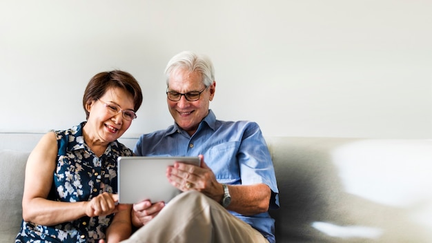 Senior couple using a digital device in a living room