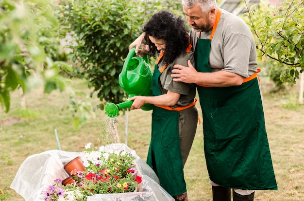 Free photo senior couple watering flowers