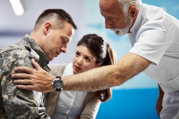 Free Photo senior doctor consoling distraught soldier who came to medical appointment with his wife at the hospital