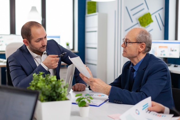 Free Photo senior entrepreneur discussing with coworker holding documents in conference during briefing businessman discussing ideas with colleagues about financial strategy for new start up company