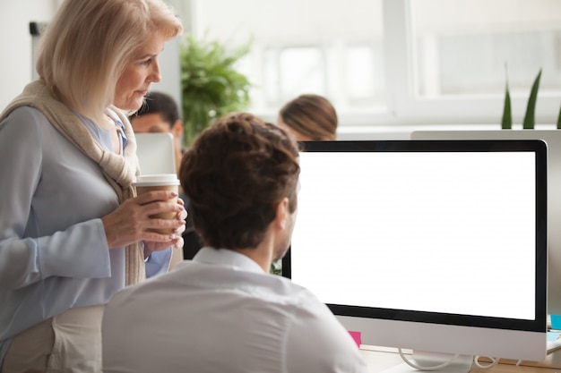 Senior executive checking annual report on computer screen helping colleague