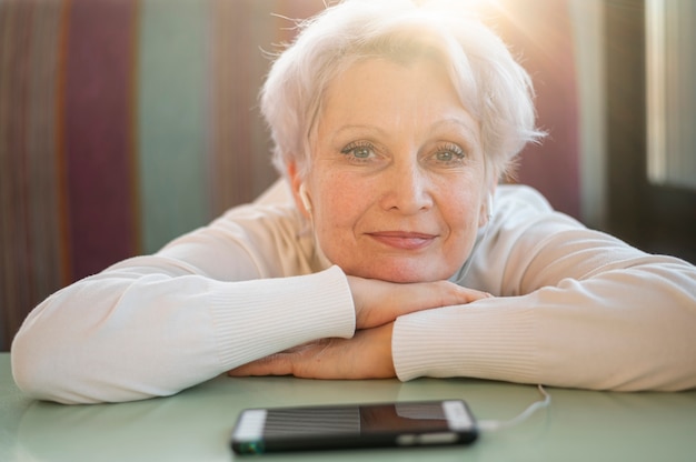 Free Photo senior female sitting with head on table and listening music