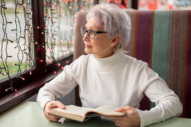 Free Photo senior female with book looking on window