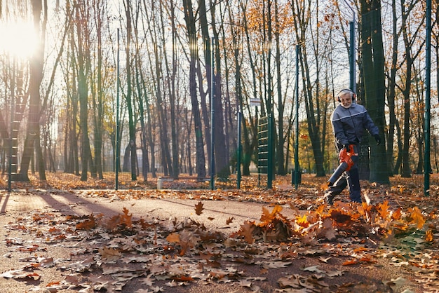 Free Photo senior gardener walking with leaf blower to clean up public area from leaves in autumn front view of