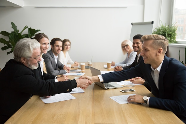 Free Photo senior investor buying startup handshaking young entrepreneur at group meeting